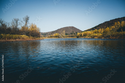Lake reflecting mountains, trees on shore, under vast sky