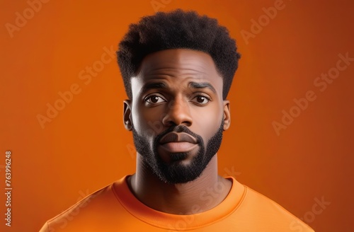 Portrait of a confused puzzled minded African American man in orange top isolated on orange background, with copy space