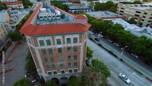 Aerial Tilt Down Shot Of Roofed Building Of The Culver Hotel In Residential City Under Clouds During Sunset - Culver City, California photo