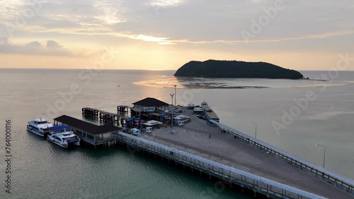 Aerial view of Thongsala Pier (Raja, Lomprayah, Seatran, Night Boat), Koh Phangan, Thailand. Forwards drone shot towards golden sunset.  photo