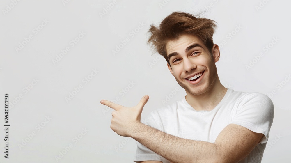 handsome young man, smiles pleasantly, dressed in casual outfit, points index finger on empty space isolated over light grey background. handsome young man, smiles pleasantly, dressed in casual outfit, points index finger on empty space isolated over light grey background.