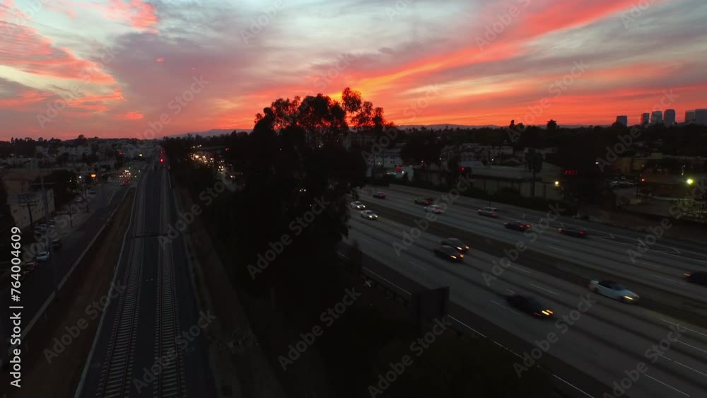 Aerial: Drone Forward Ascending Shot Of Illuminated Cars Moving On Road In Residential City Under Dramatic Cloudy Sky At Dusk - Culver City, California Aerial: Drone Forward Ascending Shot Of Illuminated Cars Moving On Road In Residential City Under Dramatic Cloudy Sky At Dusk - Culver City, California