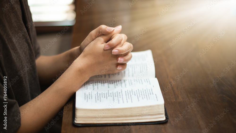 Obraz premium Christian woman's hands resting on a Bible pleading with God.