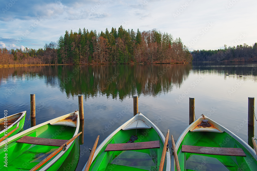 Winter landscape at a lake with forests, a cloudy sky and some boats