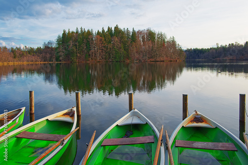 Winter landscape at a lake with forests, a cloudy sky and some boats