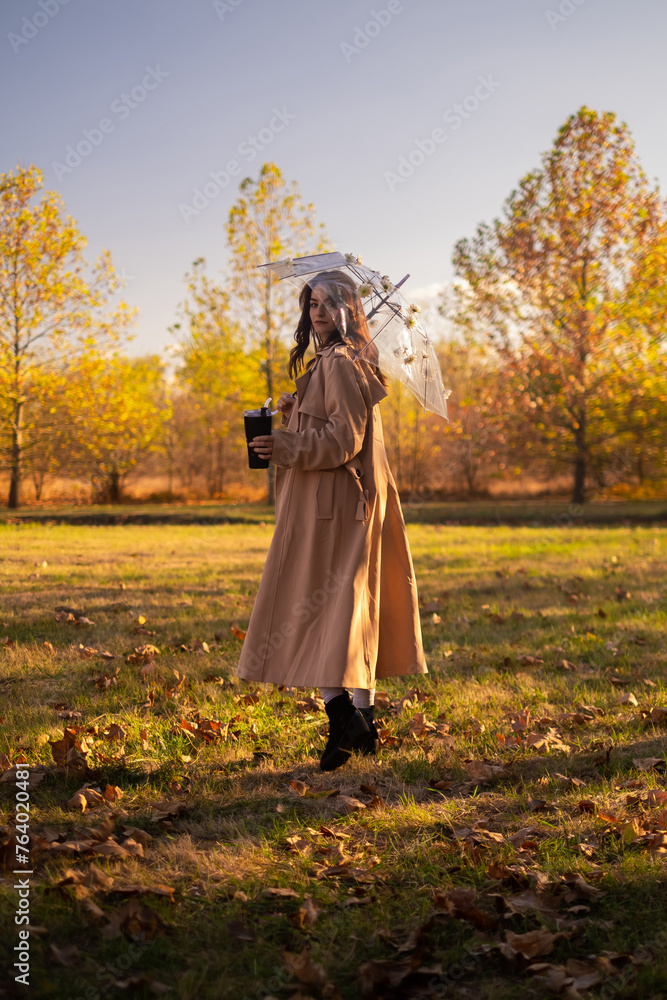 A woman in a beige coat runs in the park, holding an umbrella. She is dressed in waterproof clothing, ready for the rain. A woman in a beige coat runs in the park, holding an umbrella. She is dressed in waterproof clothing, ready for the rain.