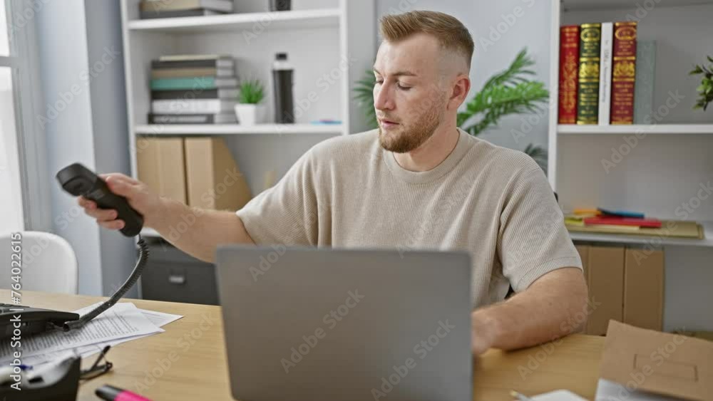 Caucasian man with beard smiles while on phone in modern office setting with laptop and desk Caucasian man with beard smiles while on phone in modern office setting with laptop and desk