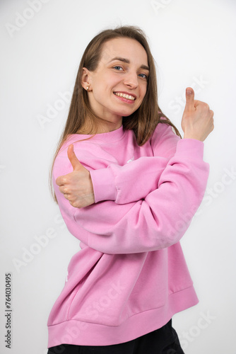 Beautiful girl in a good mood shows a gesture of both hands with thumbs up, studio shot