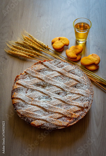 Neapolitan Pastiera Crostata, typical italian cake for Easter time exposed with ears of wheat and cookies. Filled with ricotta and candied fruit, covered with powdered sugar.