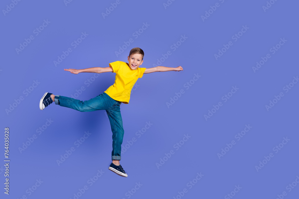 Full length photo of cheerful funny boy wear trendy clothes raise fist super mission empty space isolated on violet color background