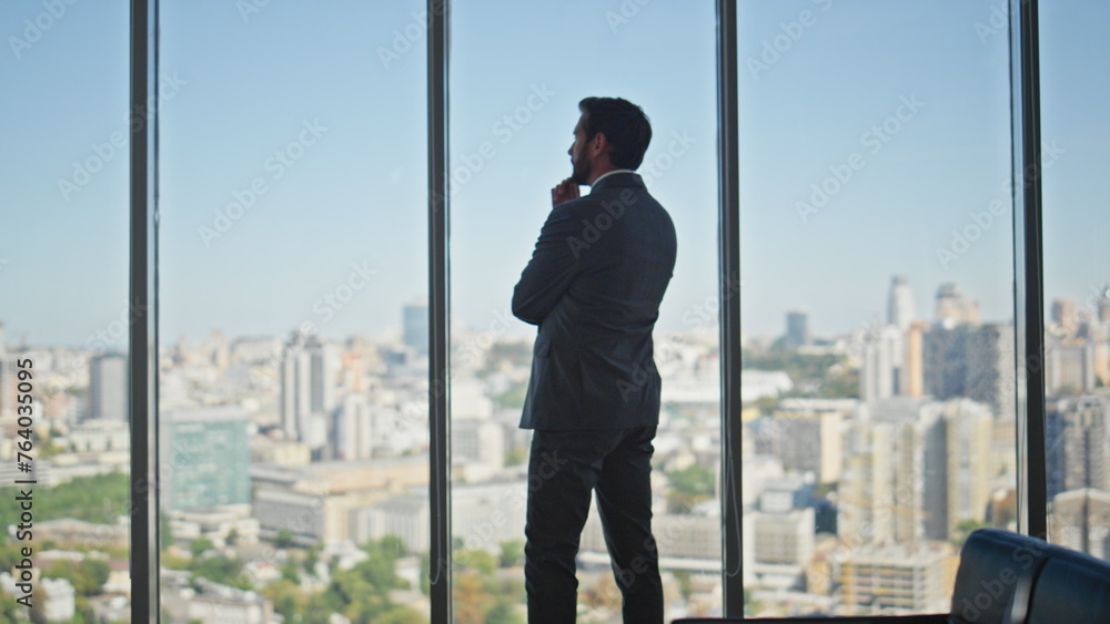 Thoughtful man looking panoramic window in office. Legal manager contemplating Thoughtful man looking panoramic window in office. Legal manager contemplating