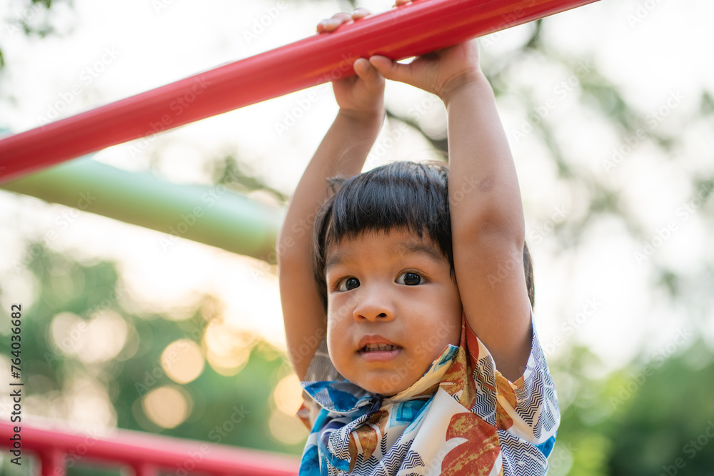 Adorable preschool boy enjoying bar lifting in outdoor playground in city park Adorable preschool boy enjoying bar lifting in outdoor playground in city park