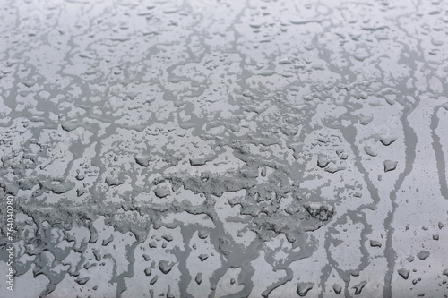 Background, texture of a black surface in flowing drops of water from melted snow and ice. Close-up photography, abstraction, top view, melting process.