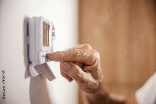 Tableau sur toile Close up of senior man's hand adjusting central heating on dashboard at home