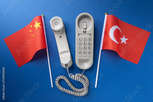 Flag of China, Turkey and old corded telephone on a blue background, concept on the theme of telephone conversations between countries