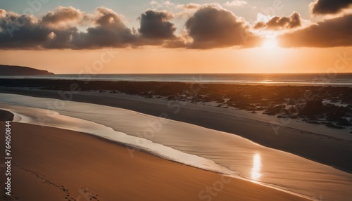 A serene beach at sunset with the golden sunlight reflecting on the wet sand and the tranquil waves, under a softly clouded sky © video rost