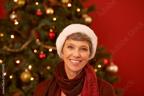 Senior, woman and portrait on Christmas with smile for celebration, holiday and festive season with tree for decoration. Happiness, wellness and Santa hat for tradition, joy and positivity at home