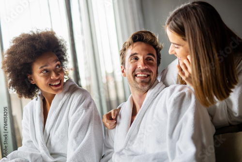 Group of happy people enjoying wellness relax weekend. Man with two beautiful women in bedroom.