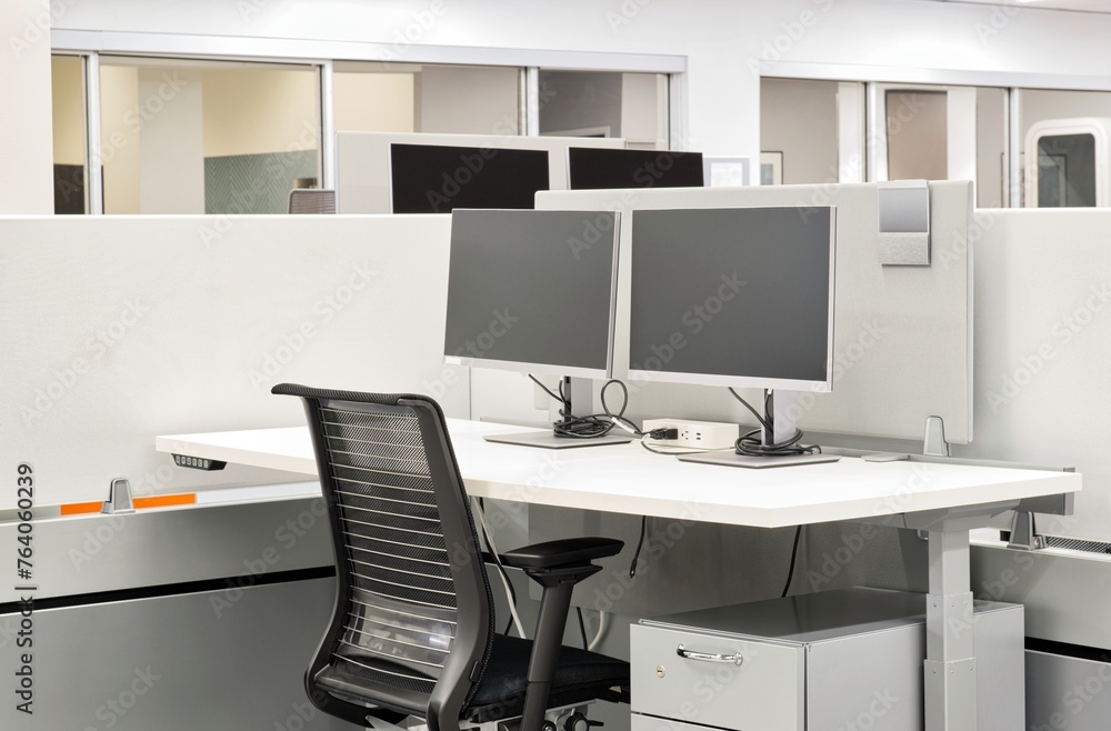 Empty office desk space with computer monitors, desk and chair at a cubicle. Working from home concept image.	