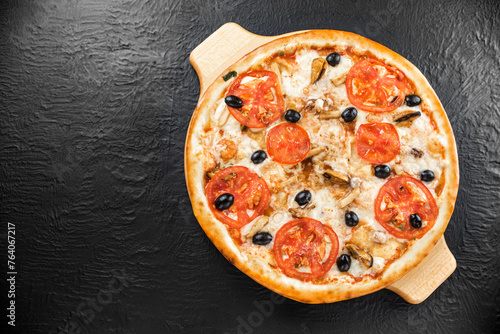Pizza naples with tomatoes on a black wooden background top view