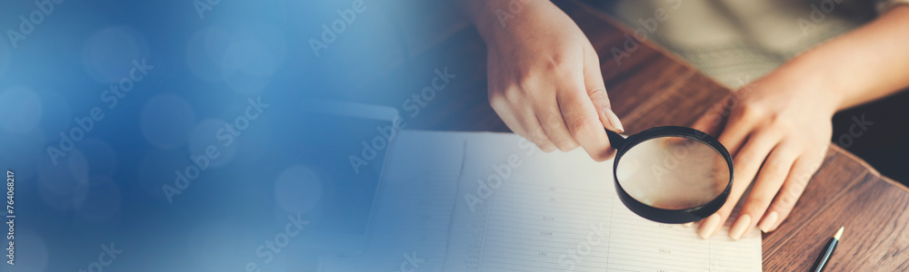 Business woman using magnifying glass to document