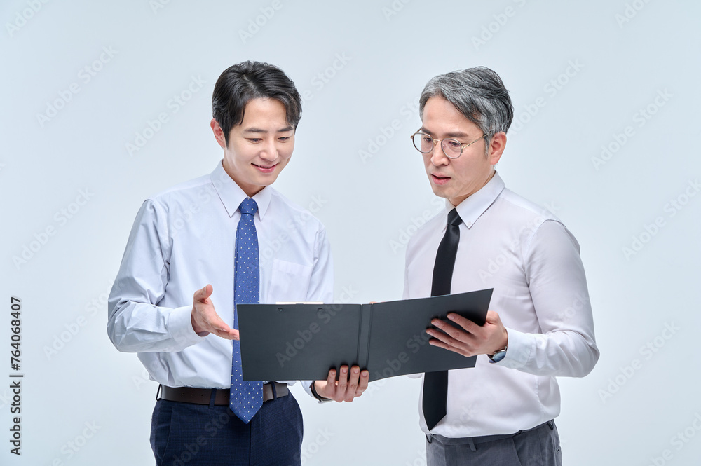 A middle-aged office worker man in a suit and glasses are holding a document file together and discussing with various confident expressions and poses. A middle-aged office worker man in a suit and glasses are holding a document file together and discussing with various confident expressions and poses.