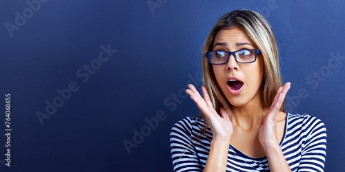 Studio, news and woman in shock with hands for promo or deal for clothes in fashion, sale and discount. Adult, female person and girl in blue background with glasses, mock up and announcement
