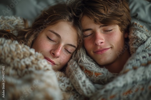 Two teenagers enjoy a tranquil moment together, cuddling under a cozy blanket with eyes closed