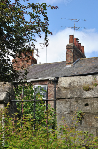 Close Up of Old Stone Boundary Wall and 19th Century Brick Buildings with Television Antennae  photo