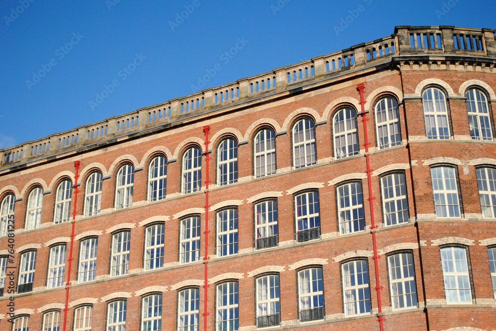 Facade of Renovated 19th Century Cotton Spinning Mill seen against Blue Sky 