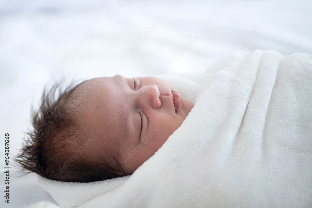 Close up, newborn baby less than one month old sleep comfortably wrapped in a blanket Close up, newborn baby less than one month old sleep comfortably wrapped in a blanket