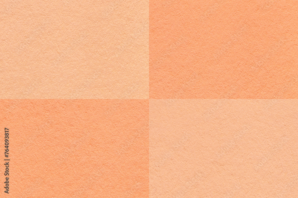 Texture of craft peach fuzz and coral paper background with cells pattern, macro. Vintage kraft cardboard