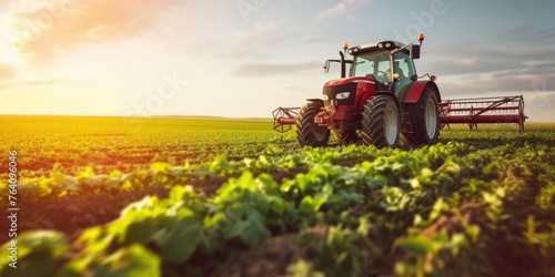 A tractor tills the soil among vibrant green crops under the warm glow of the setting sun