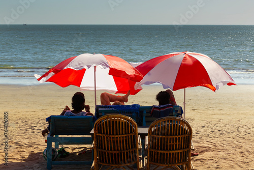Vacationers under colorful umbrellas on the ocean shore