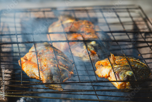 Fresh gourami fish is grilled over a burning and smoky fire