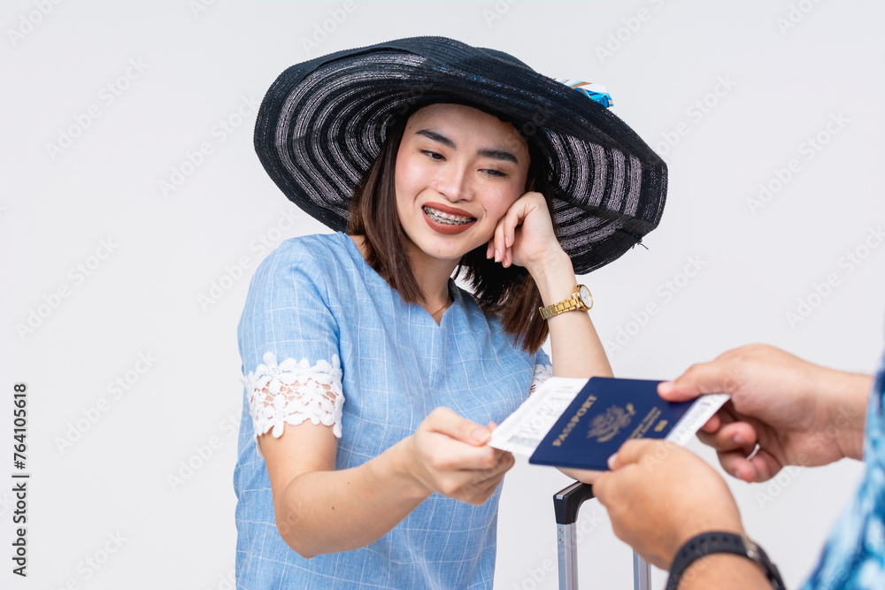 A cheerful Asian female tourist in a stylish hat receives a boarding pass inside her US passport against a white background, exemplifying travel and adventure. A cheerful Asian female tourist in a stylish hat receives a boarding pass inside her US passport against a white background, exemplifying travel and adventure.