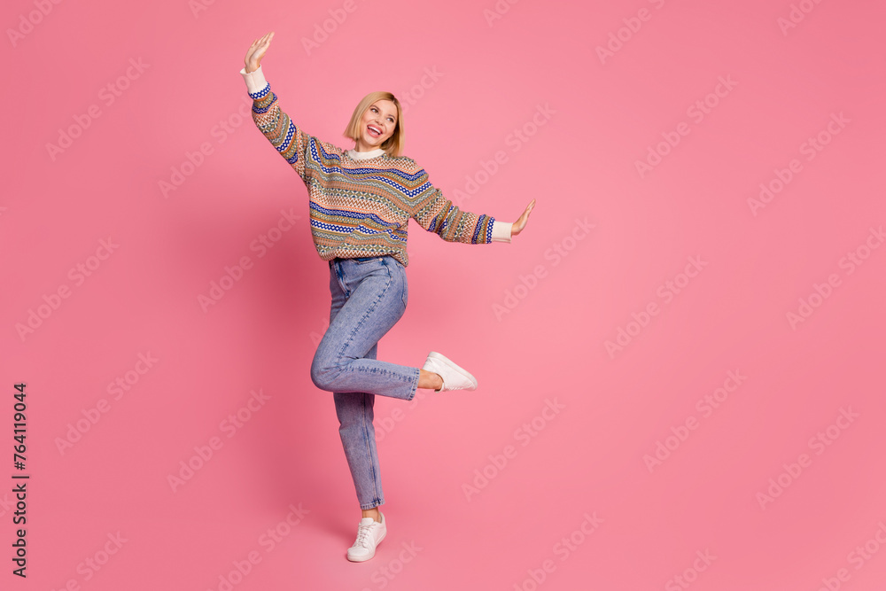 Full length photo of girlish woman dressed print sweater denim pants dancing look at sale empty space isolated on pink color background Full length photo of girlish woman dressed print sweater denim pants dancing look at sale empty space isolated on pink color background