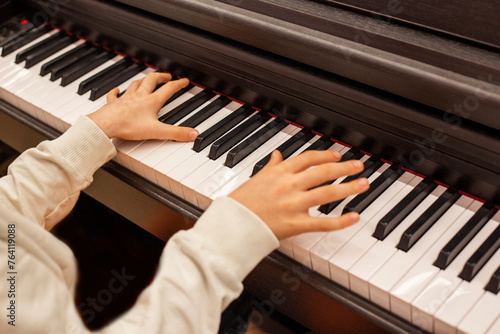 Close-up of a boy's hands on the keys of a piano, child learning to play piano photo