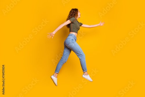 Photo of cheerful excited cute girl stylish clothes running fast hurrying seasonal sale hot offer isolated on yellow color background