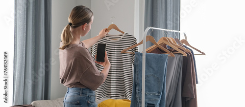 Spring cleaning,second hand,Fast fashion, the girl puts things in order in the closet. A bunch of colorful clothes. The concept of processing, second hand, eco, minimalism, consumption of goods photo