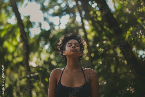 Woman peacefully meditating amidst lush forest scenery