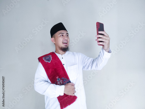 Moslem Asian man smiling happy when looking to his mobile phone photo