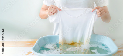 female hands washing clothes in basin. wash clothing by hand with detergent. soapy bubble water, washing powder for handwashing. Laundry, dirty t-shirt.