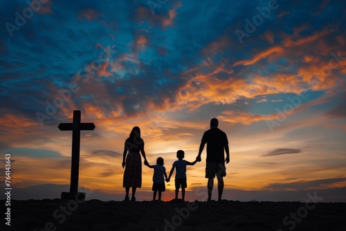 Silhouette of a family holding hands in front of a cross during a sunset, representing family values and faith.