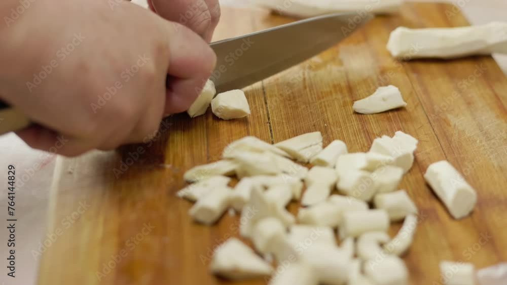 grandma cutting horseradish with a knife on a wooden board at the kitchen table, closeup with slow motion grandma cutting horseradish with a knife on a wooden board at the kitchen table, closeup with slow motion