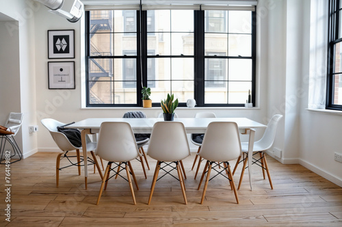 Sleek Minimalist Dining Setup: Long White Table, Matching Chairs, and Stunning Black Windows