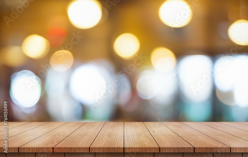 Empty wooden table top with lights bokeh on blur restaurant background.