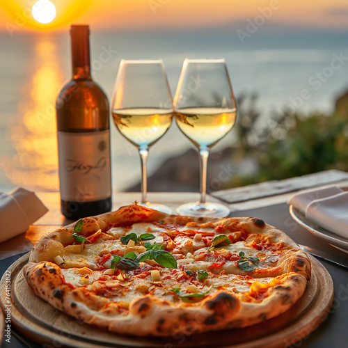 Italian pizza with glasses of white wine at luxury restaurant with a sea view at sunset