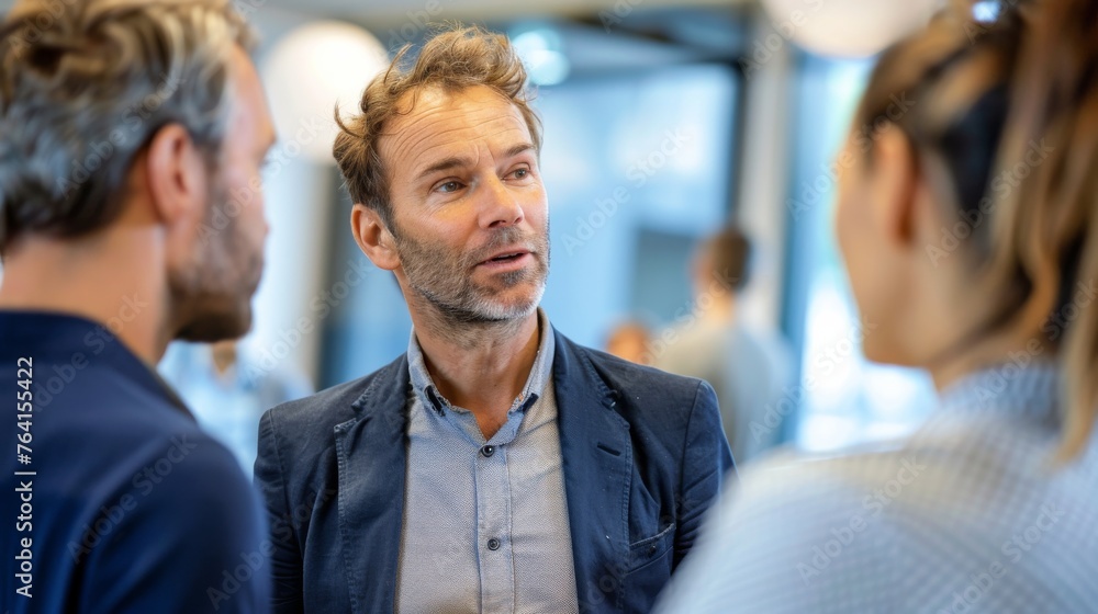 A man engaged in conversation with two other men, discussing intently and gesturing. The trio is focused on the interaction, showing active listening and exchanging thoughts. A man engaged in conversation with two other men, discussing intently and gesturing. The trio is focused on the interaction, showing active listening and exchanging thoughts.