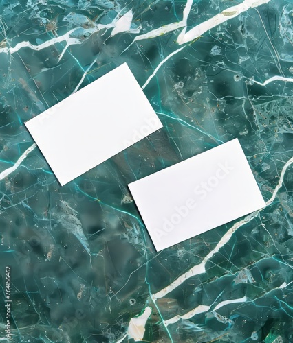 Two blank business cards lie on marble surface.